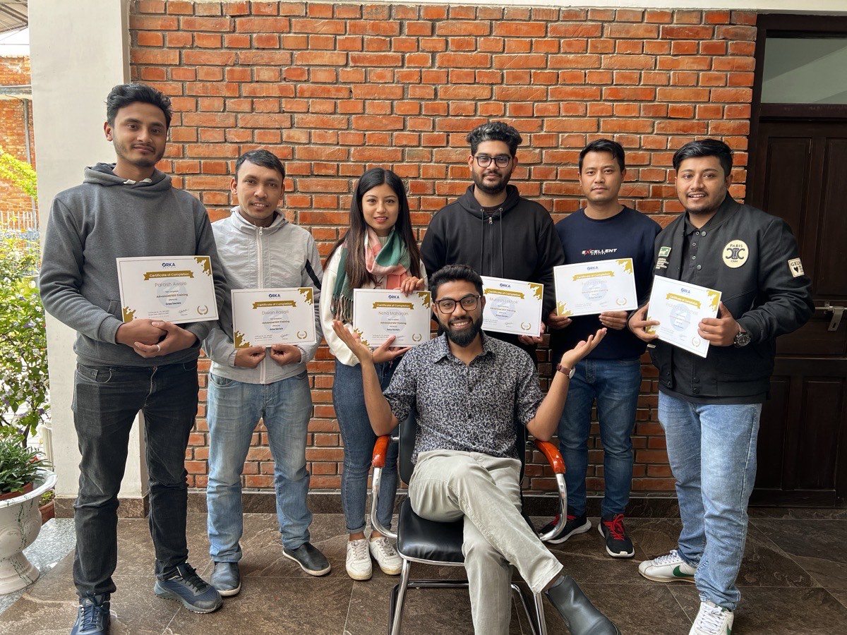 SEO Mastery Course graduates holding certificates after completing the 12-month trajectory.